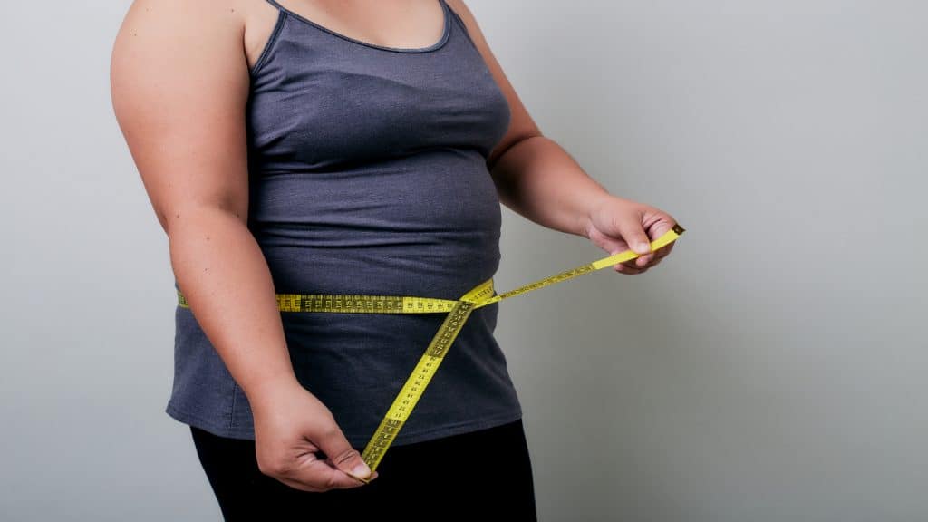 A woman measuring her fat 34 inch waist
