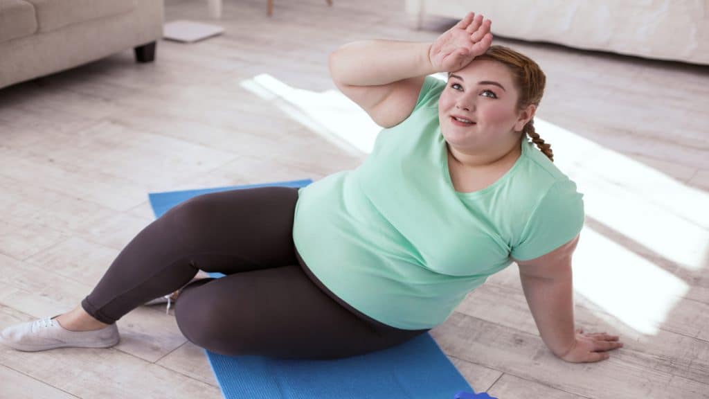 A woman with a sixty four inch waist sat on an exercise mat