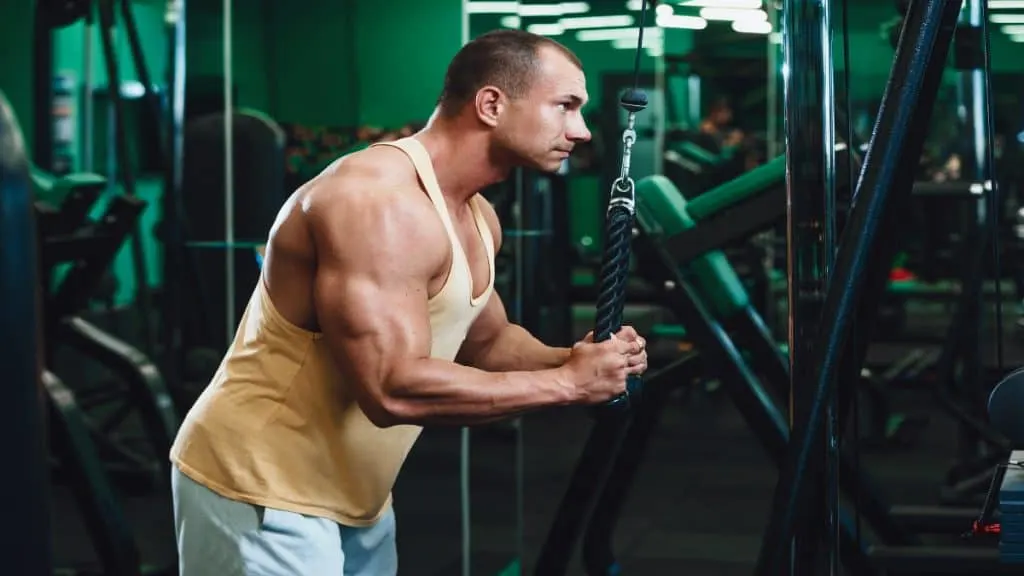 A muscular man working his horse shoe triceps in the gym