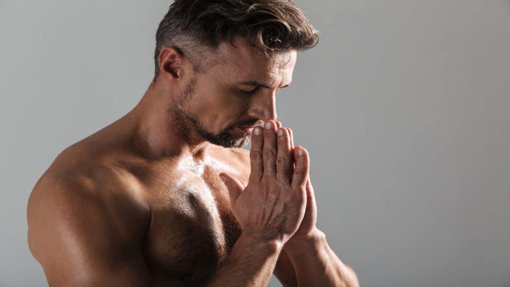 A muscular man praying