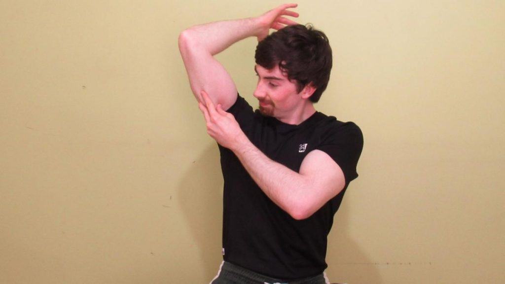 A man holding his sore tricep muscle