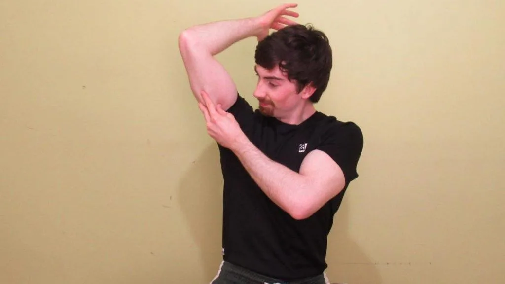 A man holding his sore tricep muscle