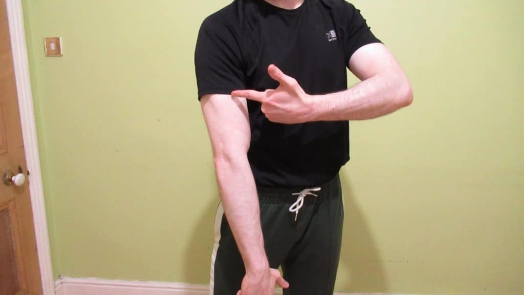 A man pointing to his arm because he has triceps cramp