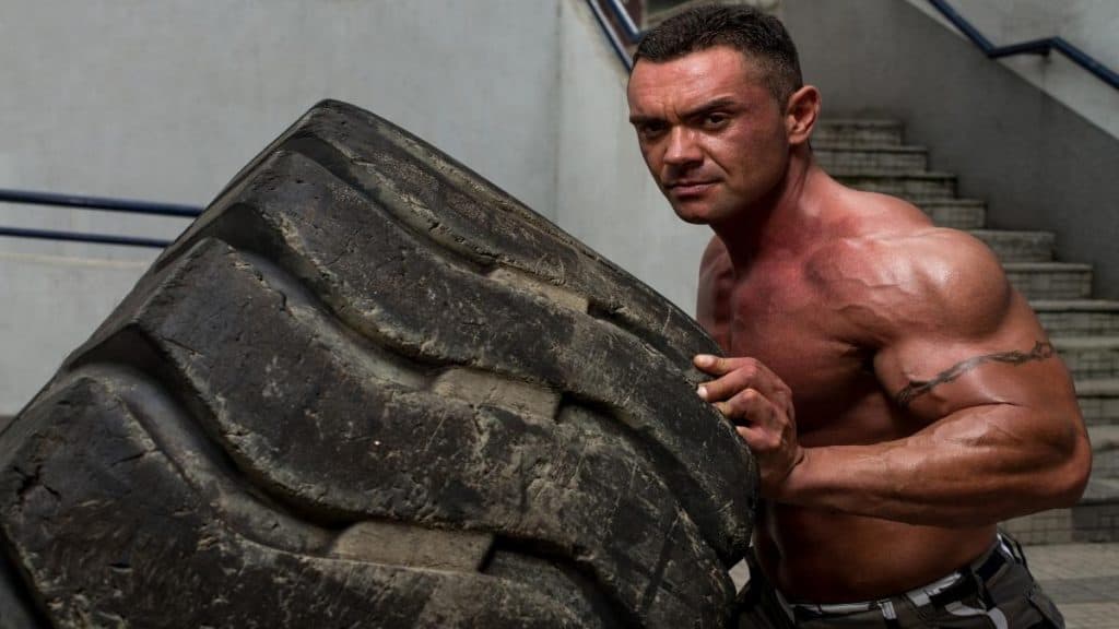 A bodybuilder with 30 inch shoulders flipping a tyre