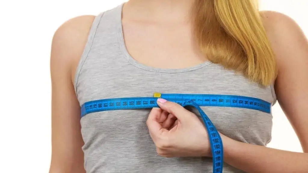 A woman measuring her 32 inch chest to determine her size