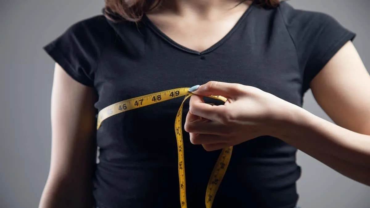 A woman measuring her 33 inch chest to see what size it is