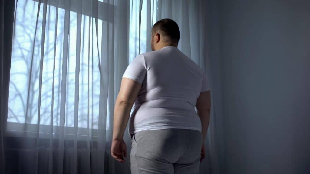 An obese man with 50 inch hips looking out the window