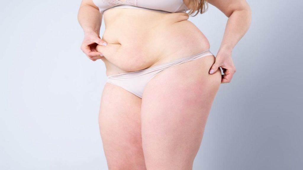 A woman pinching the fat on her 50 inch hips