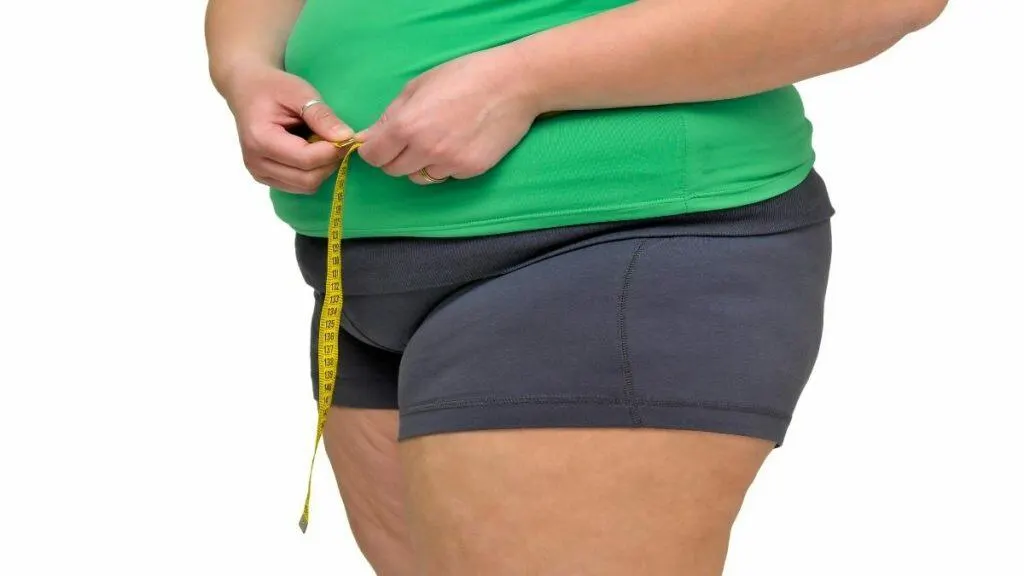 An obese woman measuring her 53 inch hips