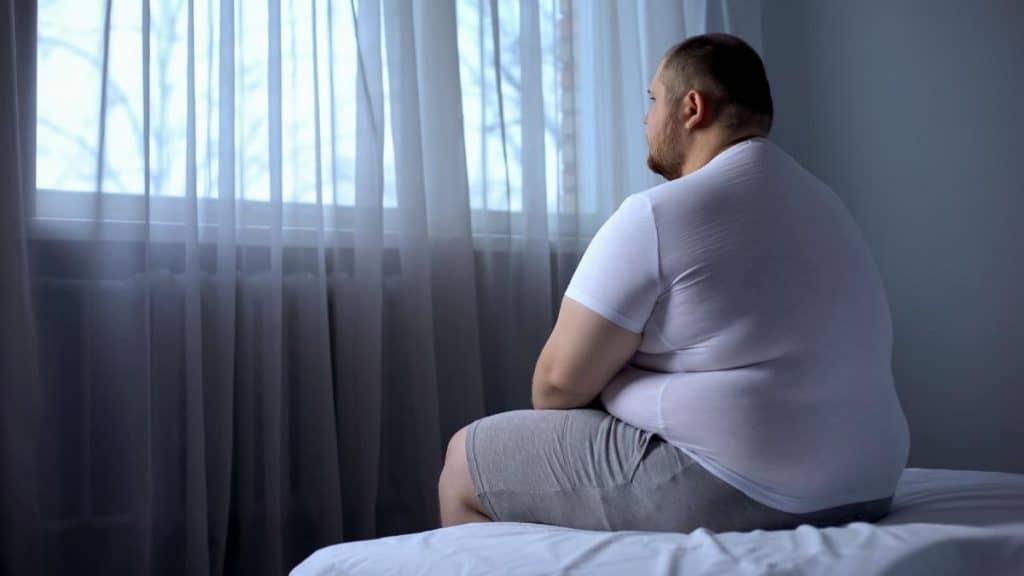 An overweight man with 56 inch hips sat on his bed