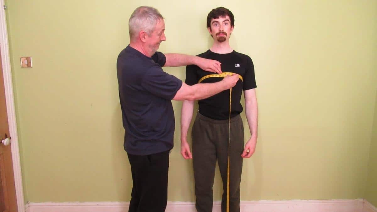 A man getting his chest circumference measured to see if he has an average male chest size