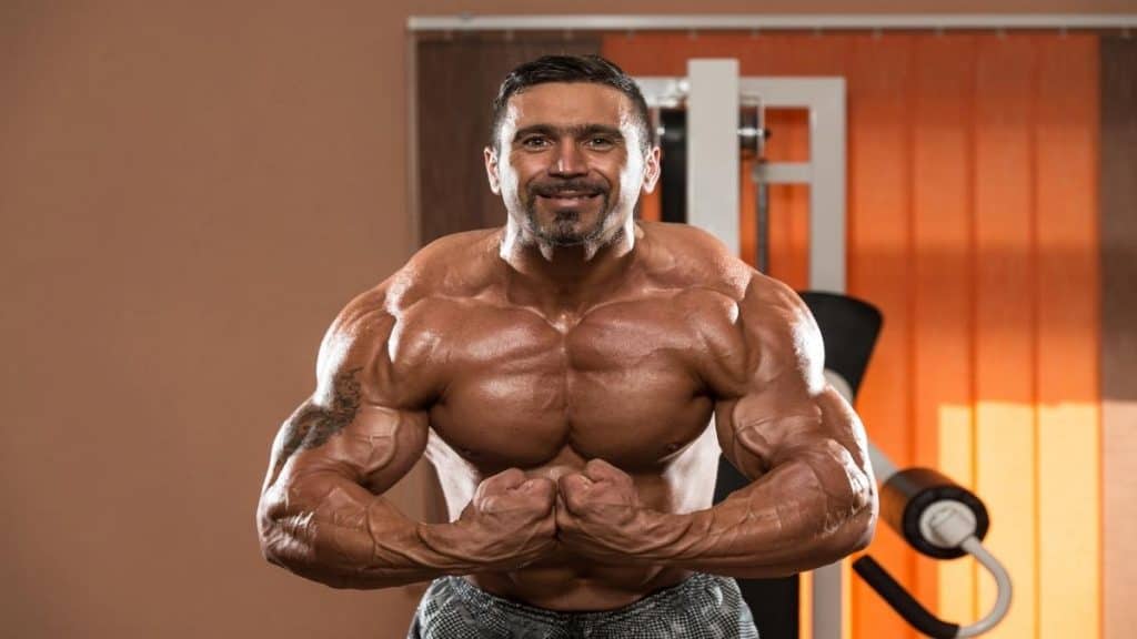 A wide bodybuilder showing that he has some of the biggest and broadest shoulders ever