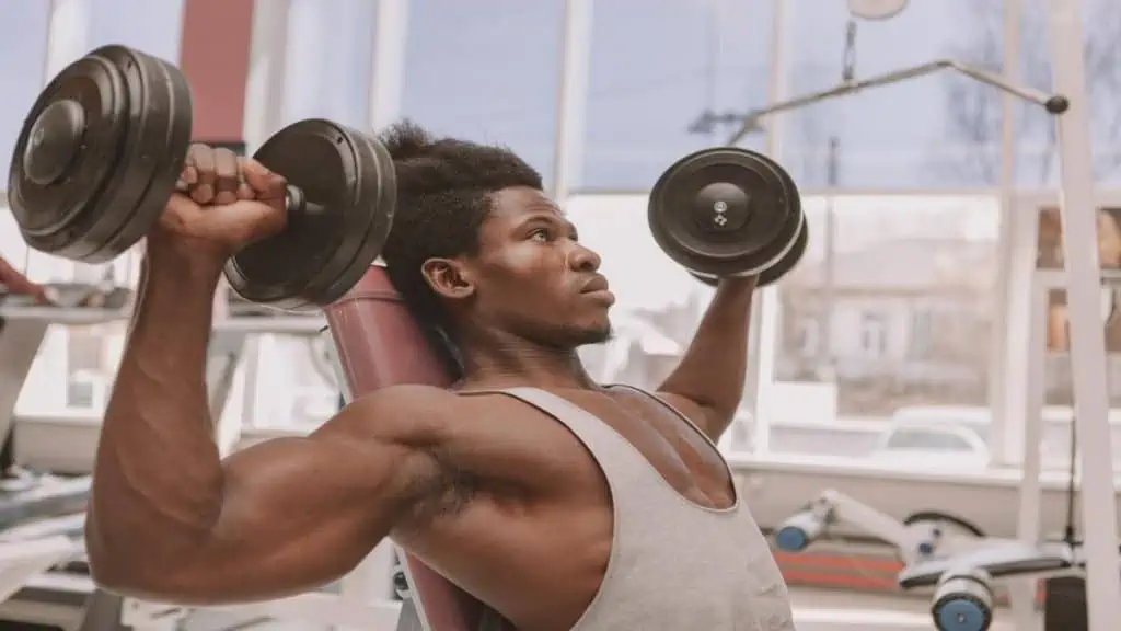 A muscular man doing a shoulder press