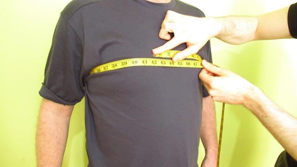 A man demonstrating where to measure your chest as a male