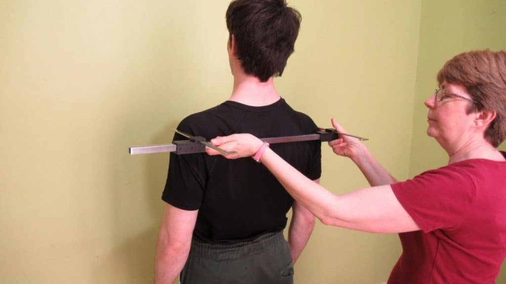 A man and a woman demonstrating where to measure your shoulders