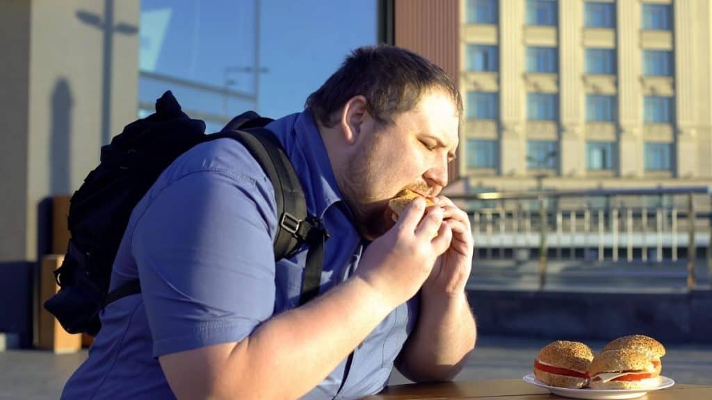 A man with 10.5 inch wrists eating a burger