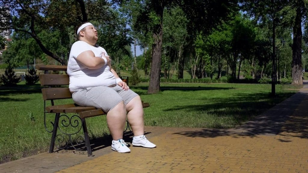 An overweight man with 100 inch hips sat on a bench