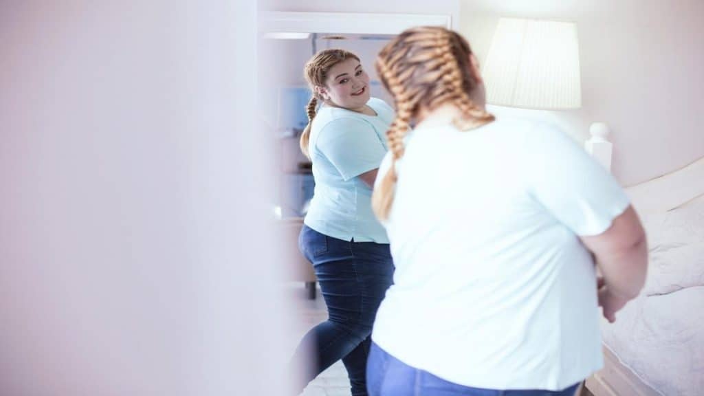 An overweight girl looking at her 70 inch booty in the mirror