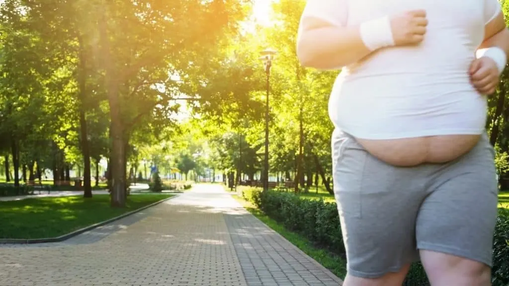 An obese man with 80 inch hips jogging in the park