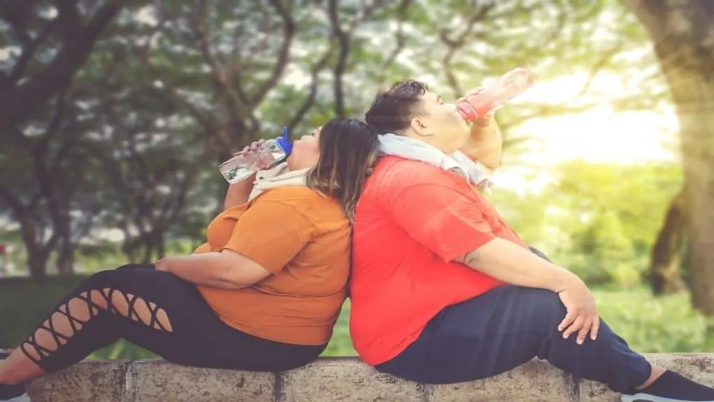 Two obese people with 99 inch hips sitting in the park