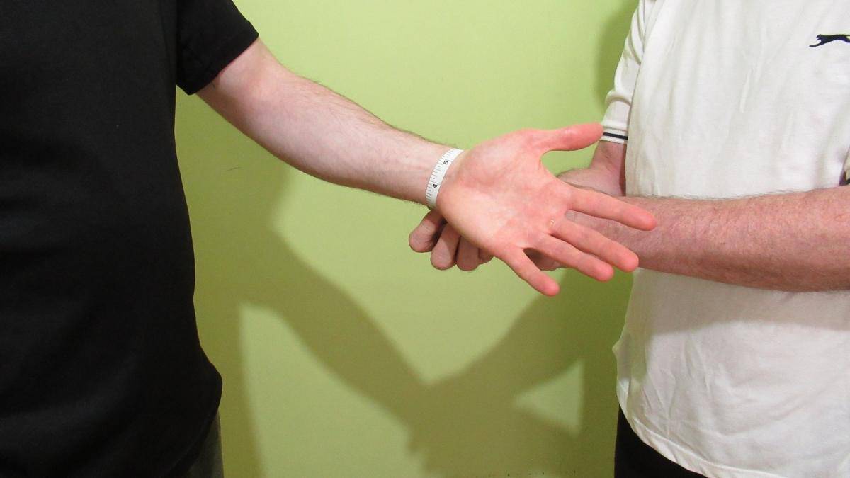 A man getting his wrists measured to see if he has an average wrist size for males