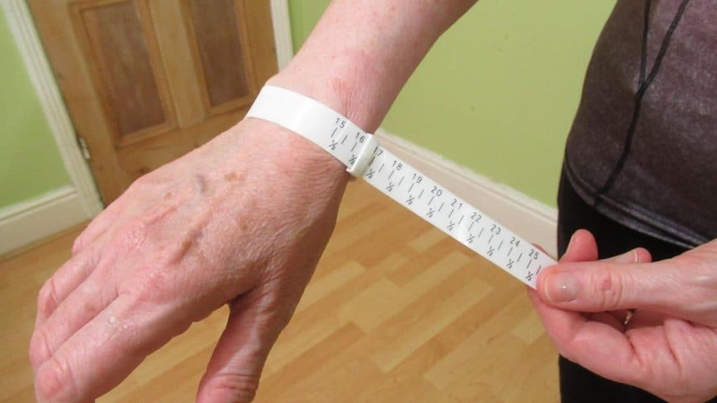 A female measuring her wrist to see if she has an average wrist size for a woman