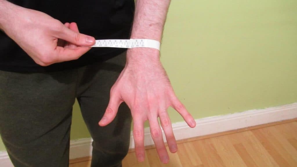 A man demonstrating how to measure your wrist size and circumference with a tape measure