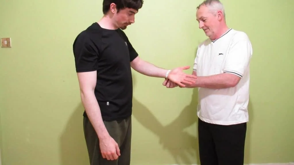 A man measuring another man's wrist circumference to determine his frame size