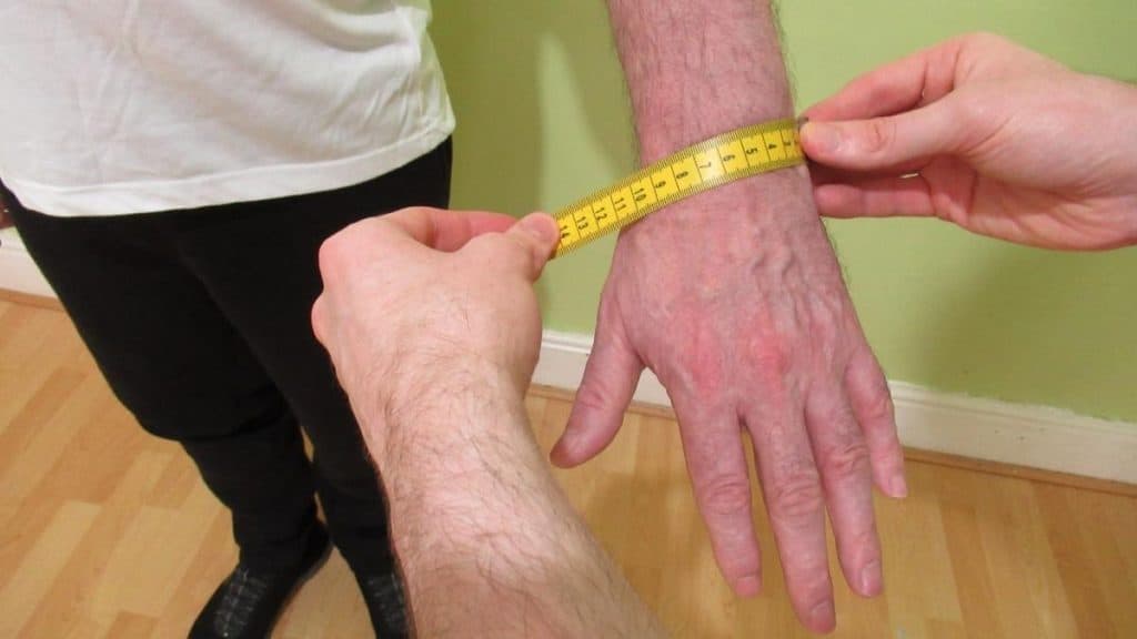 A man taking a wrist width measurement with a tape measure