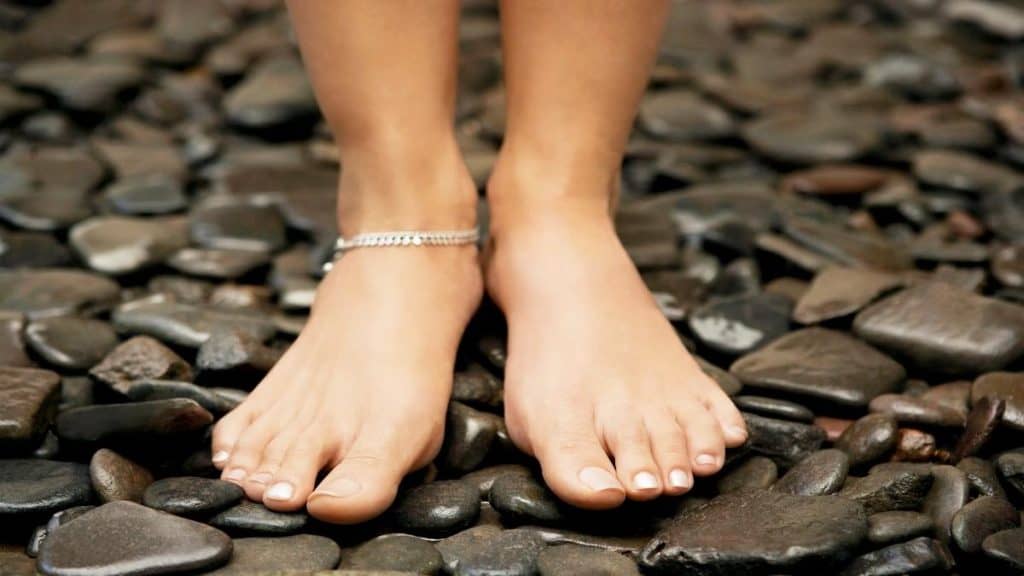 A woman wearing an ankle bracelet that is around the average anklet length