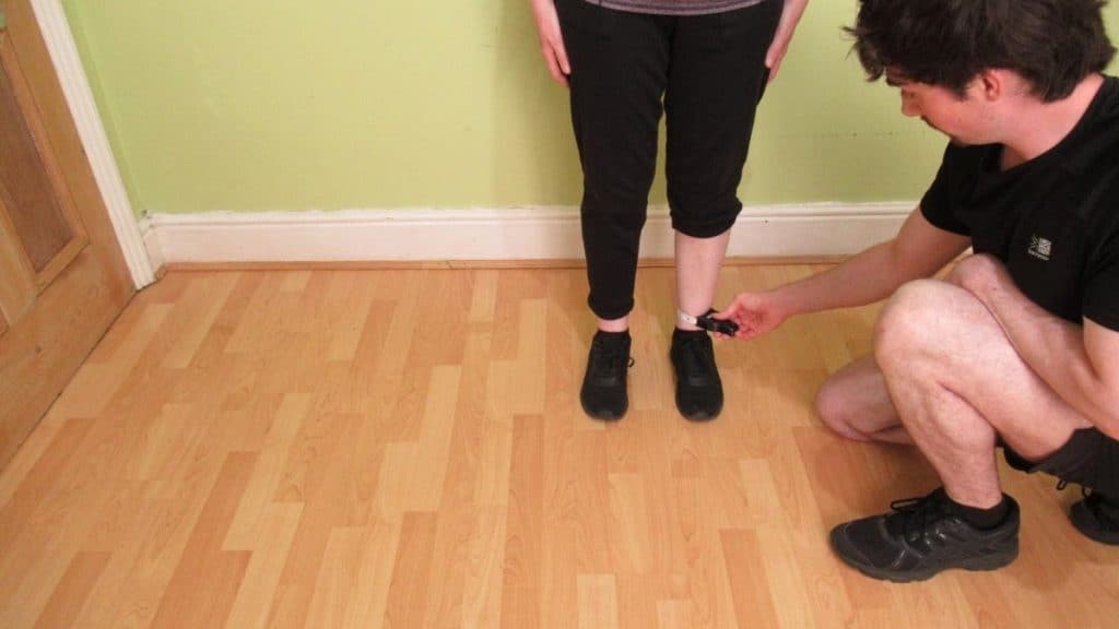 A man showing how to measure your ankle circumference