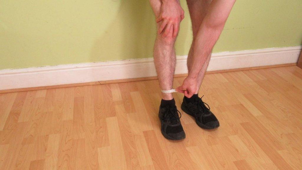 A man showing how to measure your ankle size with a tape measure