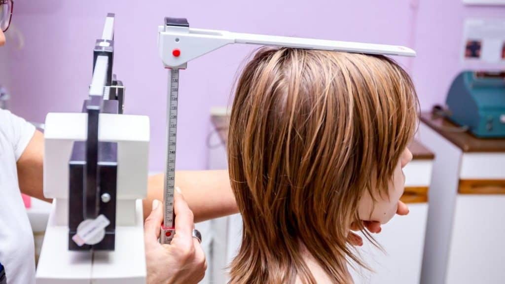 A girl getting measured to see if she has the average 12 yr old height