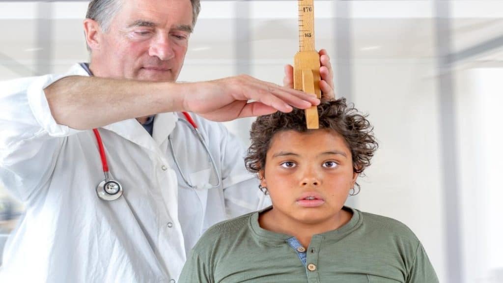 A doctor measuring the height of a 14 year old boy