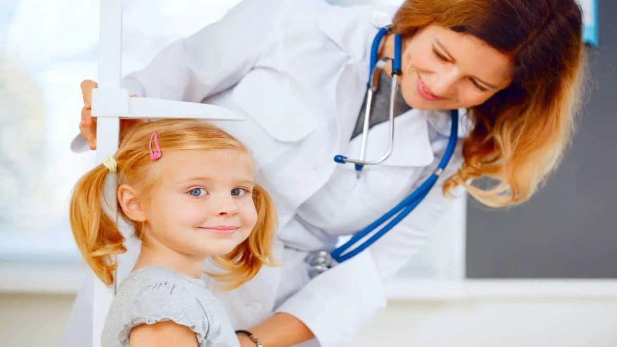 A three year old girl getting measured to see if she is of an average 3 year old height