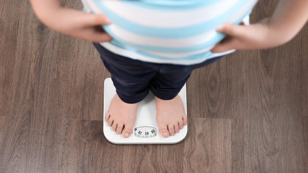 A boy weighing himself to see if he has an average 5th grader weight