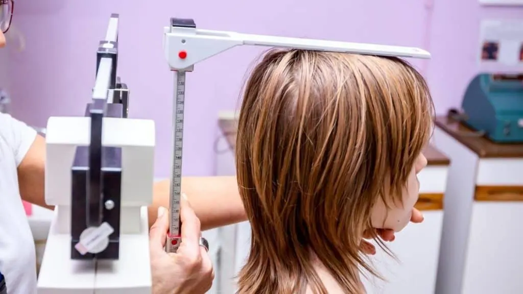 A girl getting measured to see if she has an average 9th grader height