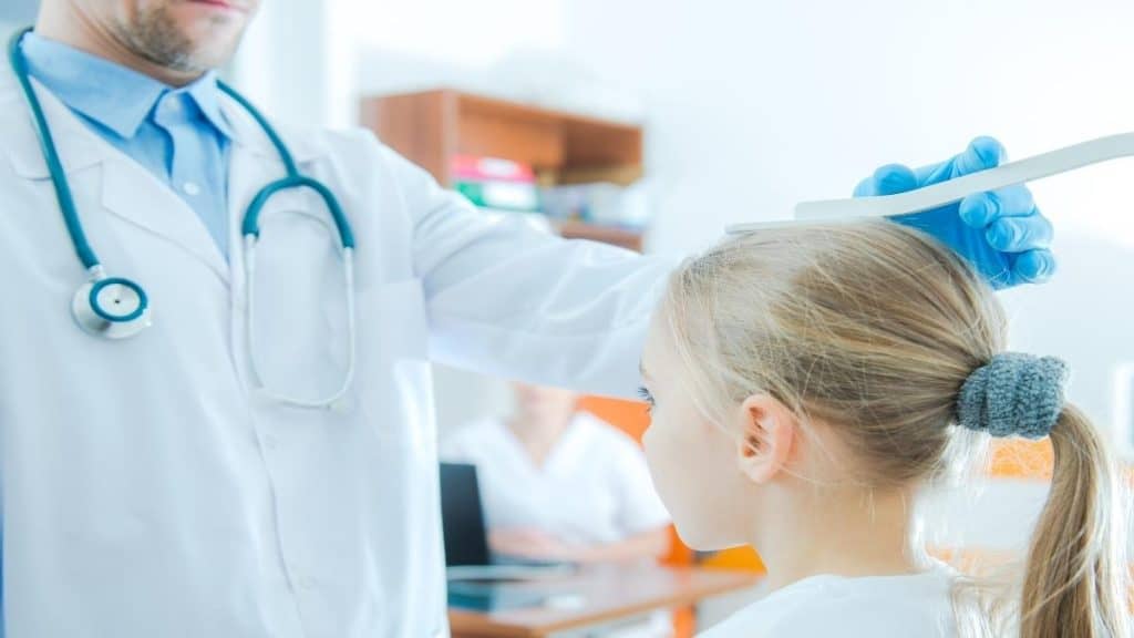 A doctor measuring a girl to see if she is the average height for a third grader