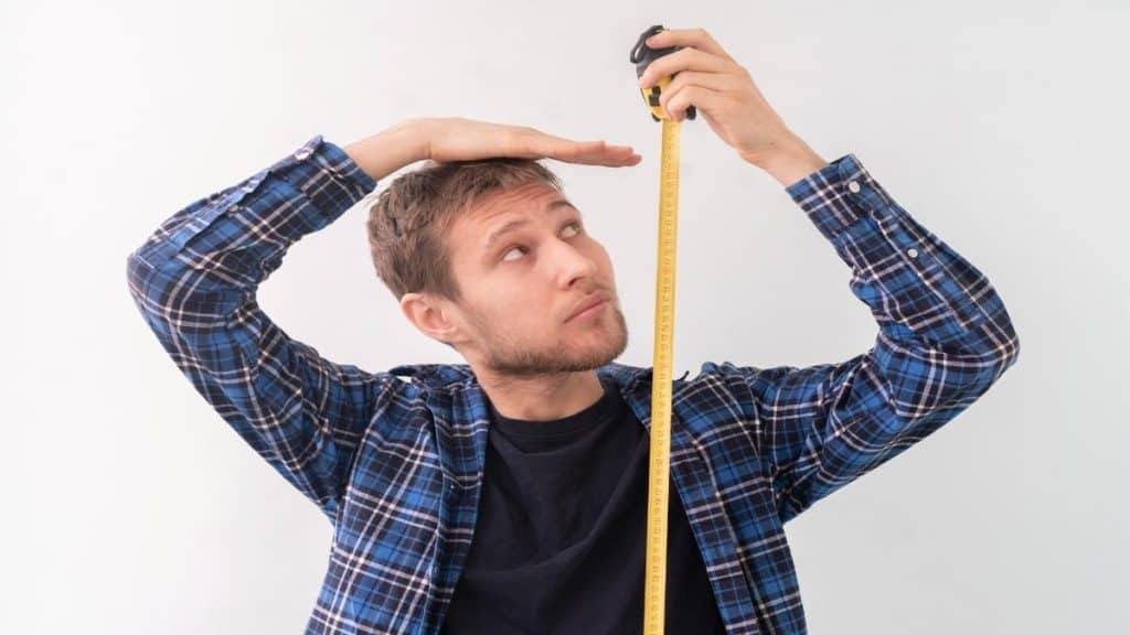 A millennial man measuring his height