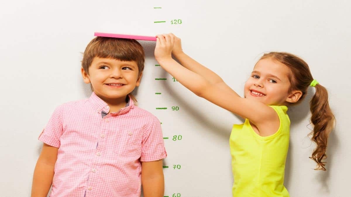 A boy getting measured to see if he is the average height of a kindergartener