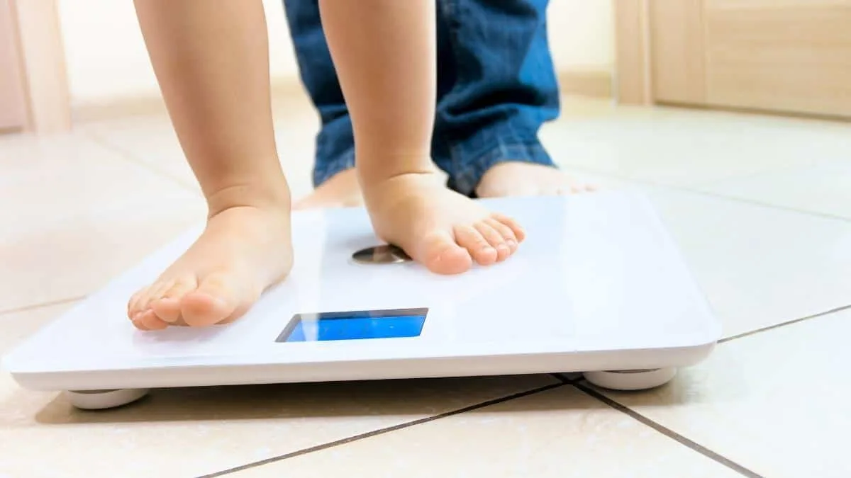 A boy checking to see if he is of an average weight for 4 year olds