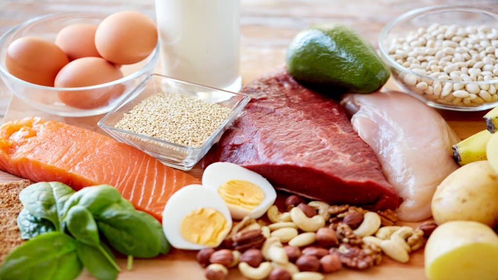 Nutritious foods laid out on a table, including fish, meat, dairy, nuts, and beans