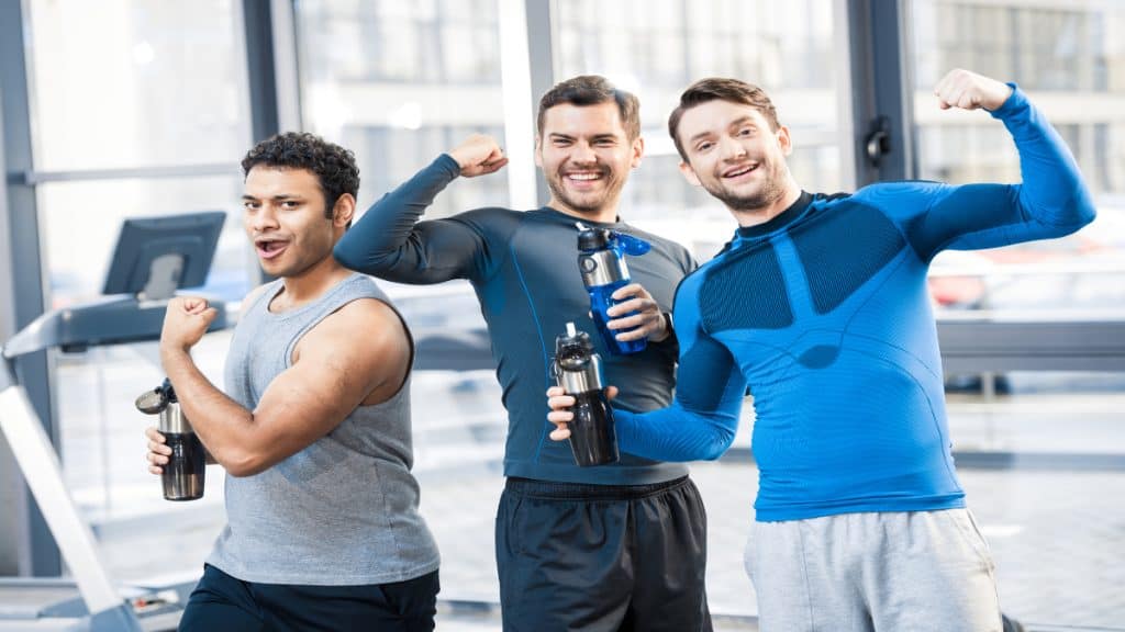 Three men flexing at the gym