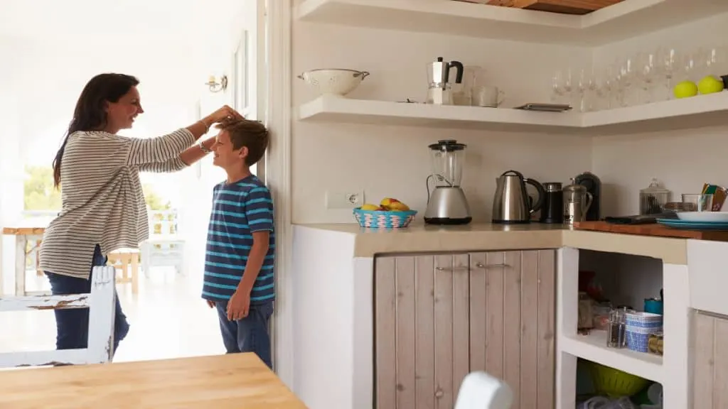 A mother measuring the height of her son