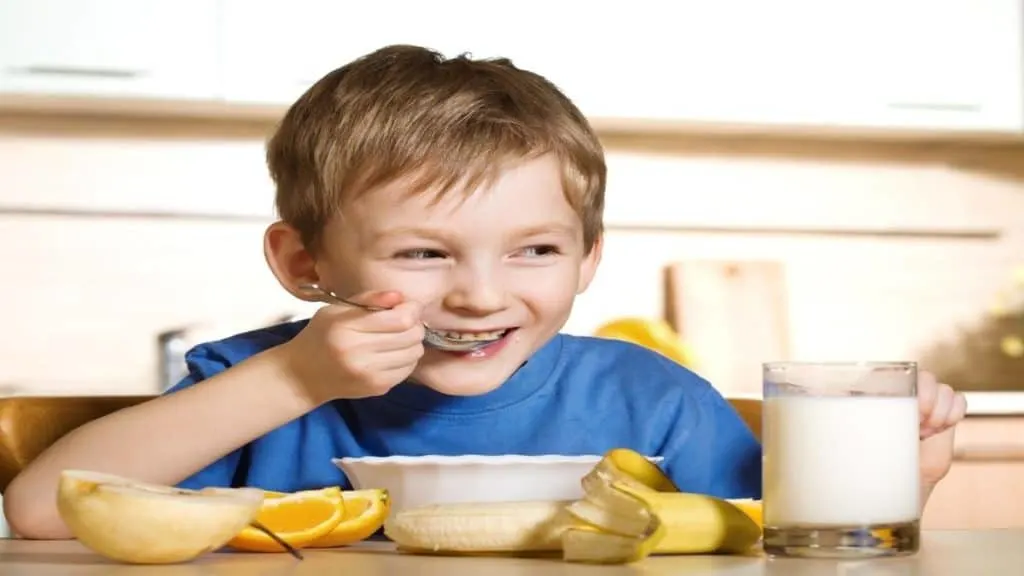 A three year old boy eating his breakfast