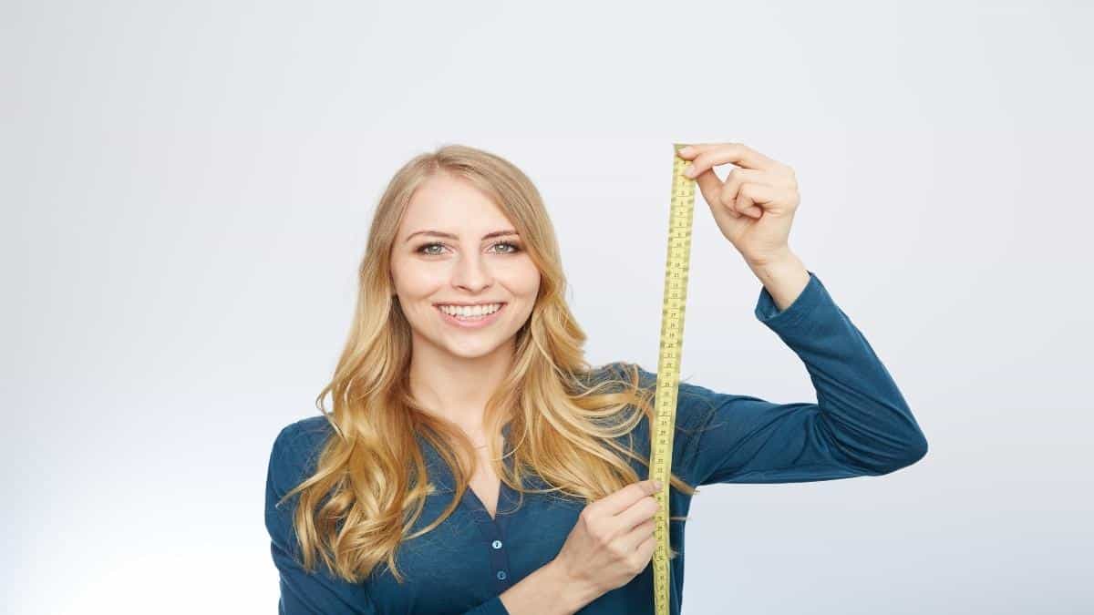 A 5'3 girl measuring her height to see if she is short or tall