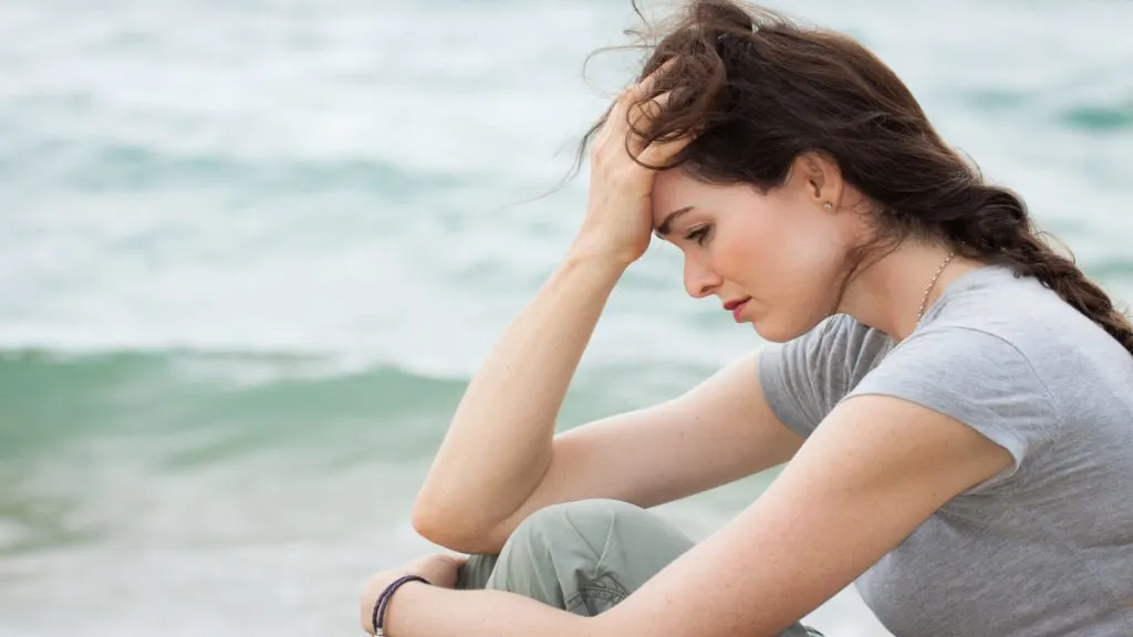 A sad woman sat by herself at the beach