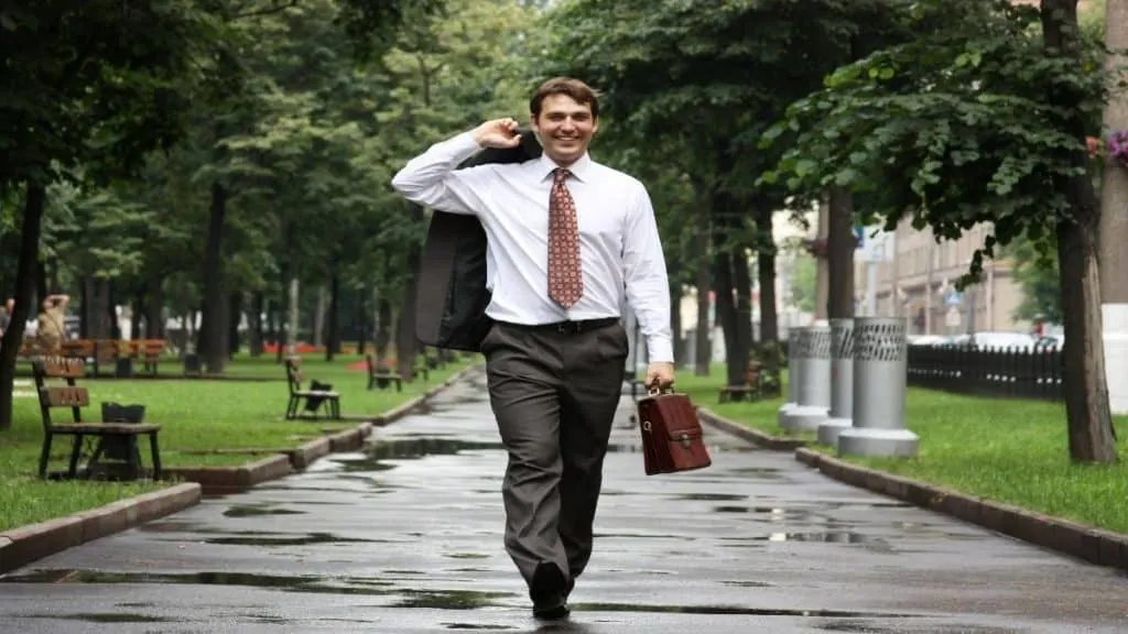 A smartly dressed man walking in the park