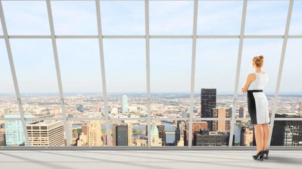 A tall woman in high heels looking out her office window