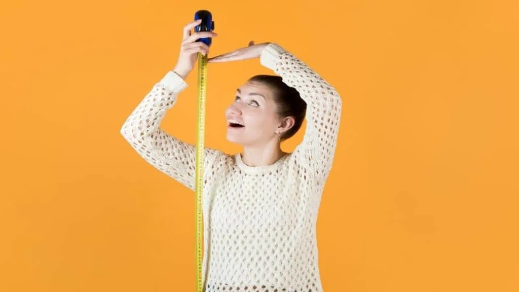 A woman measuring her height with a tape measure